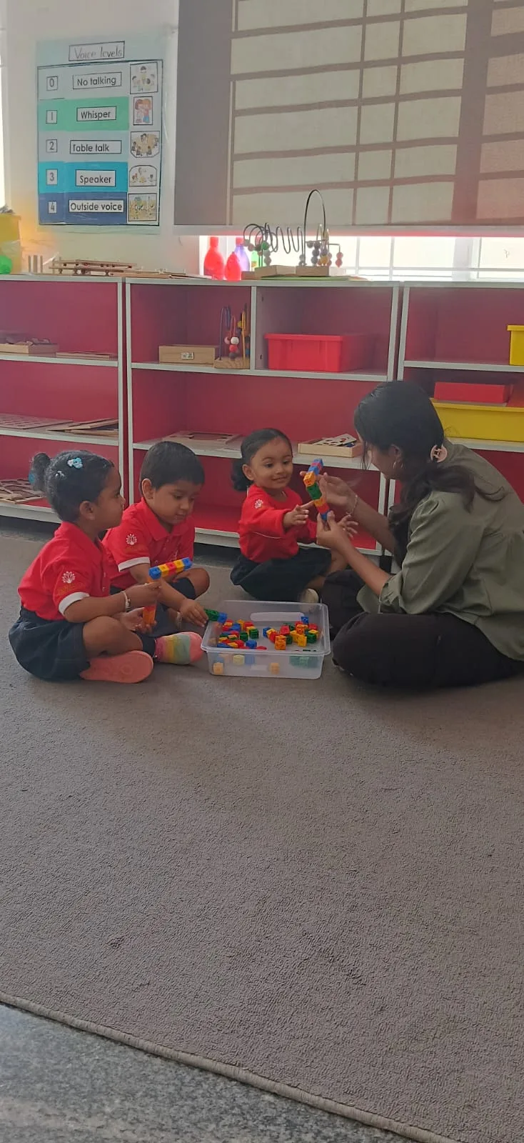 Early years students in school uniform building with a teacher