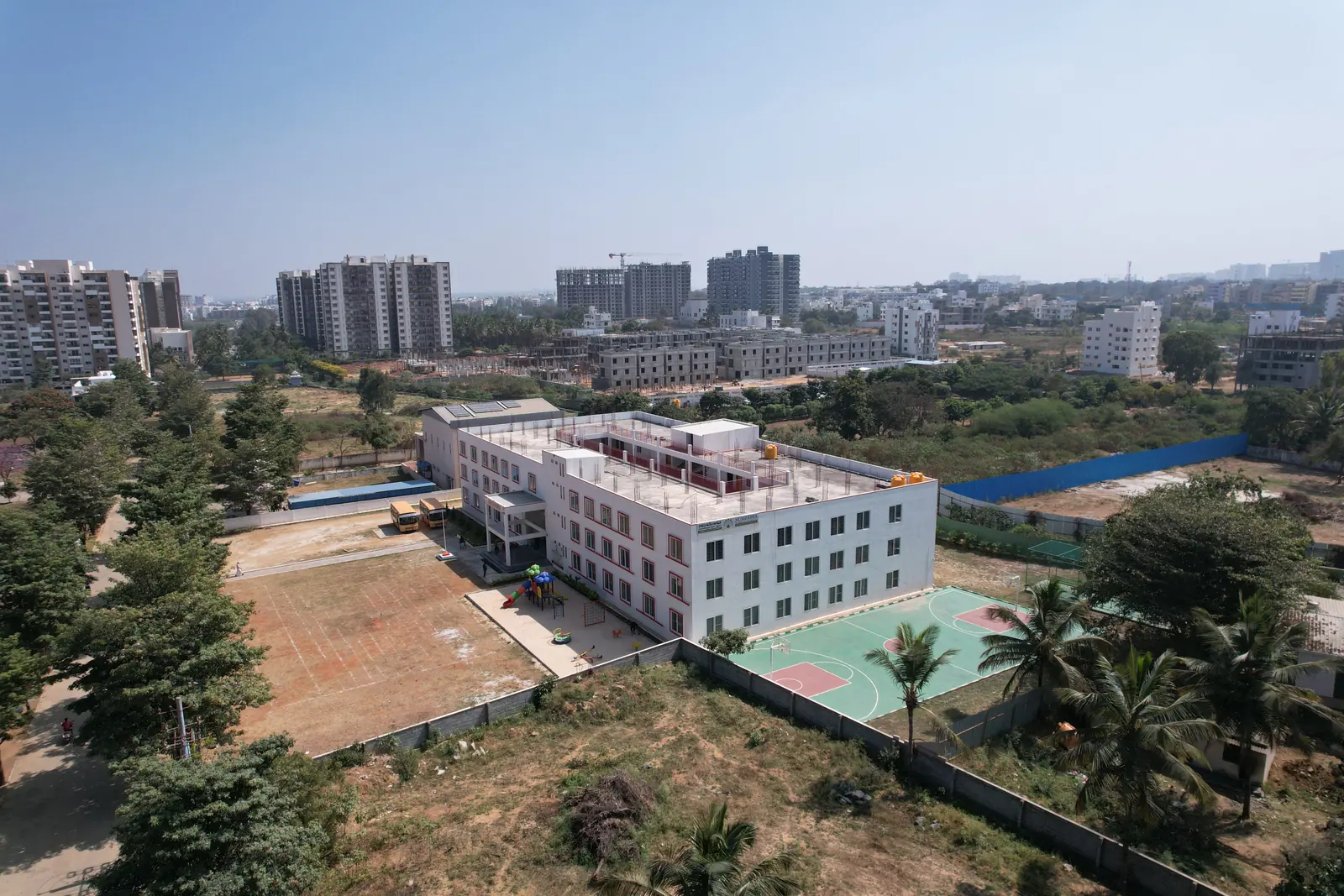 Aerial view of the Sumedha International School campus and its red-trimmed buildings surrounded by greenery