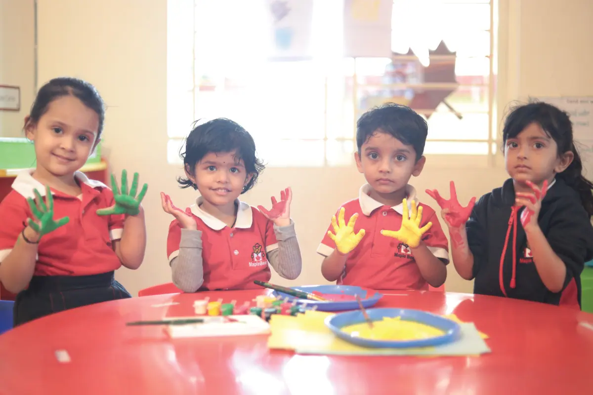 Young children proudly holding up their paint-covered hands after an art session