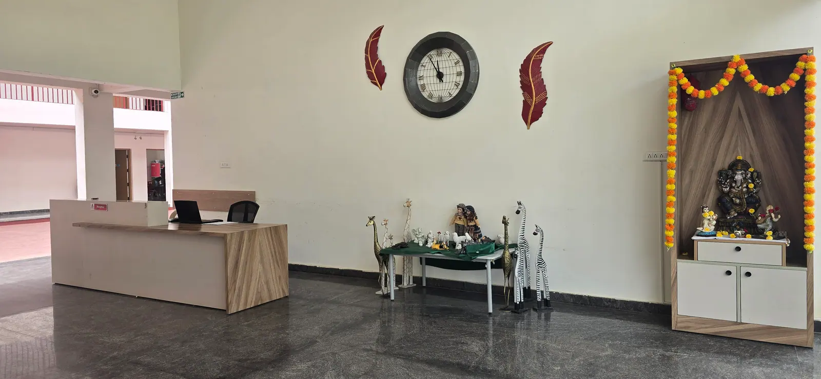 School reception with the front desk, a large wall clock and a decorated shrine