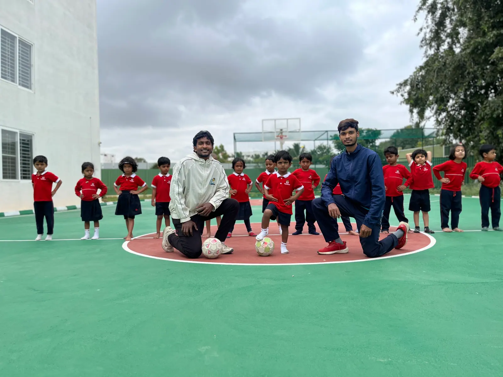 Coaches leading young students through a football drill on the school ground